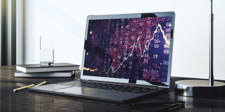 A computer monitor on a desk with a financial chart, depicting algorithmic trading.