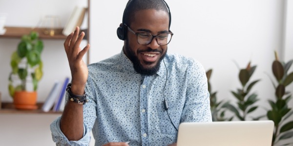 A customer success manager sitting at a desk and talking to a customer from his computer.