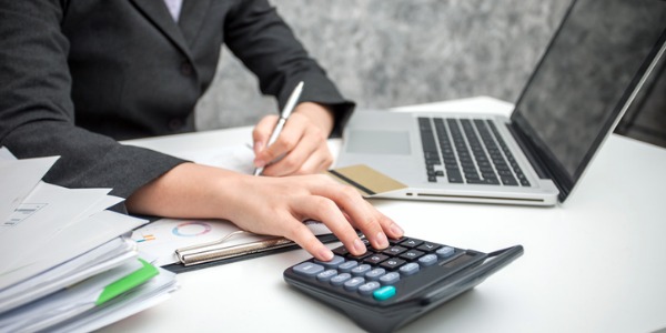 A financial clerk sitting at her desk and using a calculator.