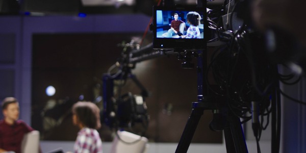 A talk show host sitting on the set with their guest.