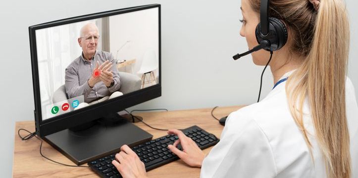 A remote patient monitoring specialist talking to an elderly patient on the computer.