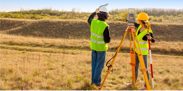 Two surveyors outside, measuring distances.