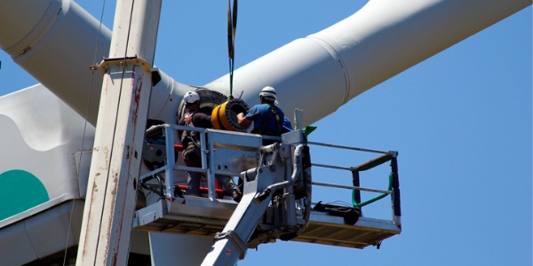 Two wind turbine technicians repairing a turbine.