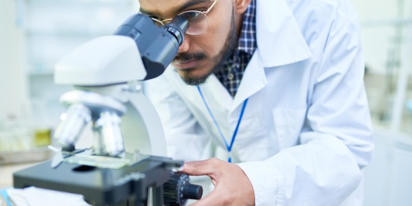 An epidemiologist looking through a microscope.