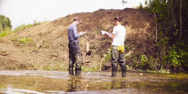 Two conservation scientists taking water samples outdoors.