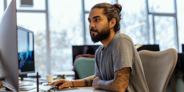 A blockchain developer sitting at a desk and working on his computer.